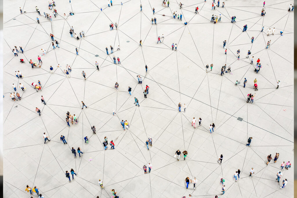 Aerial view of a crowded, geometric plaza with people walking along intersecting lines and patterns.