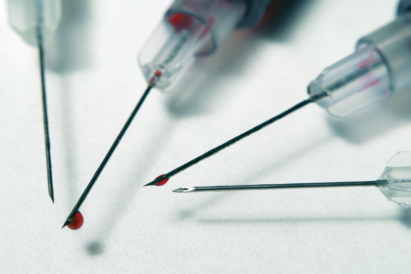 4 needles with blood drips on the syringes