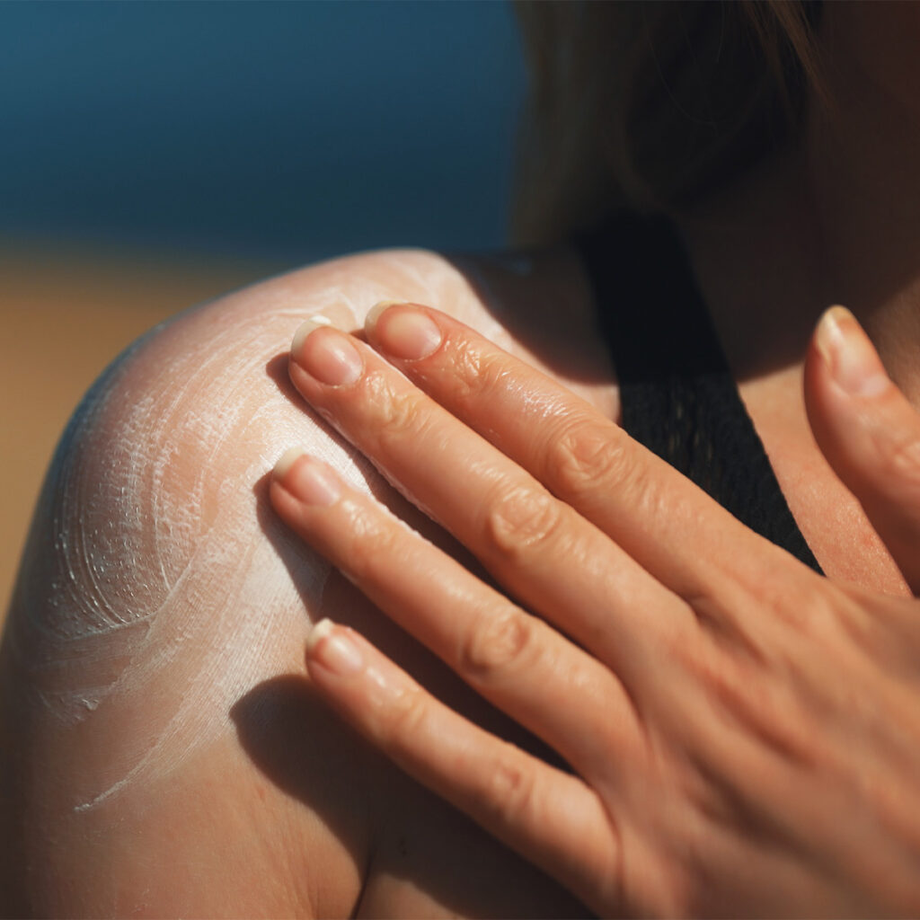 Close-up of woman smearing sunscreen on her shoulder