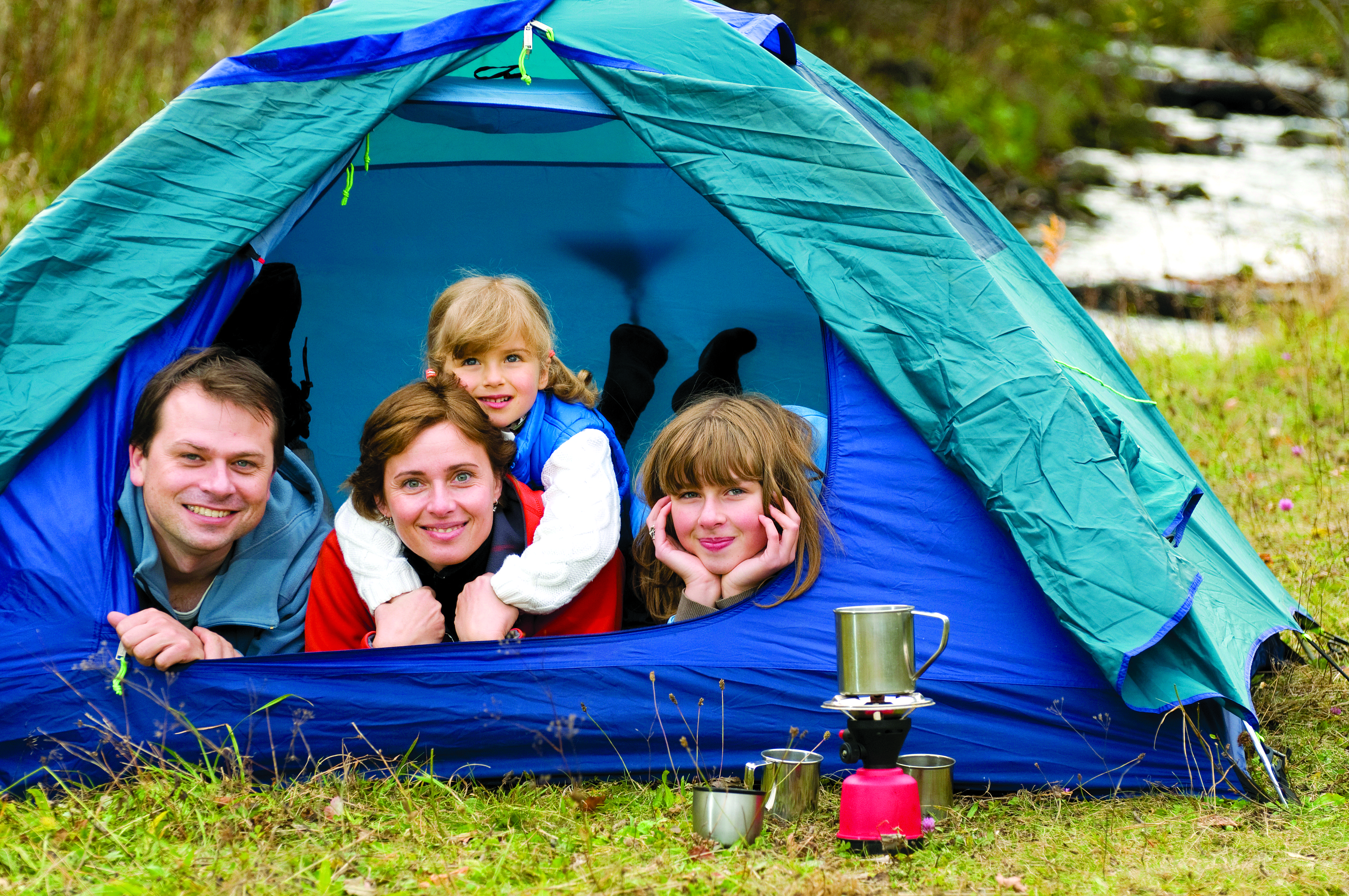 Happy family smiling and looking out from inside a tent