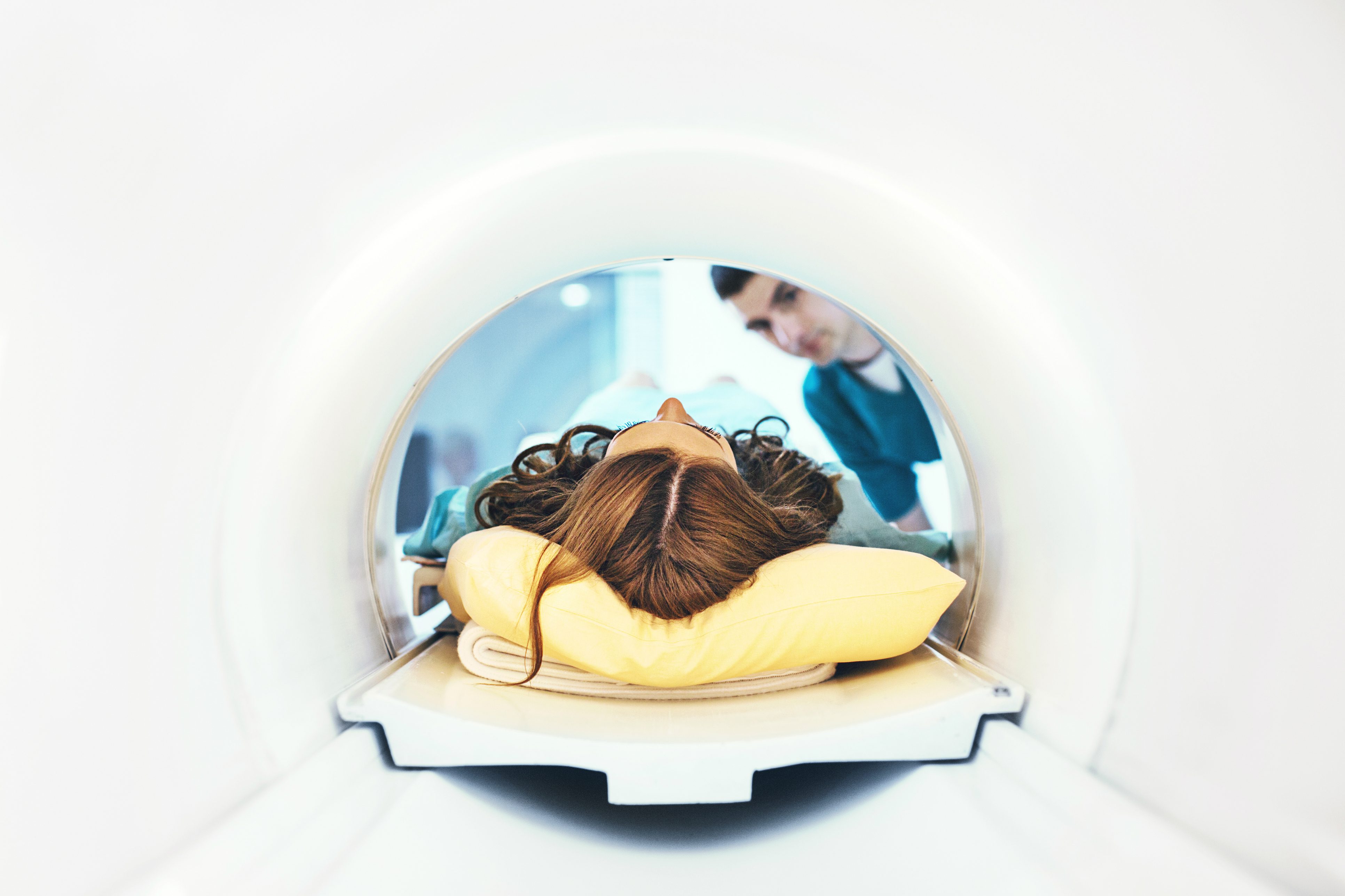 Woman in an MRI machine with an attendant looking on