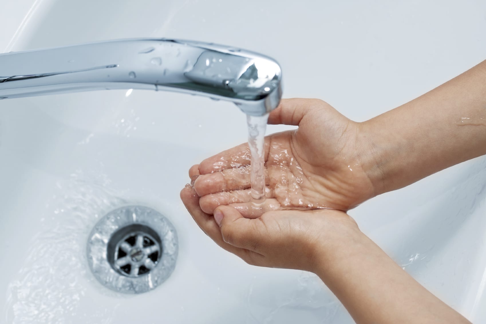 Close-up of hands under running water faucet
