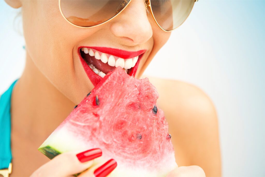 woman with red lipstick eating watermelon