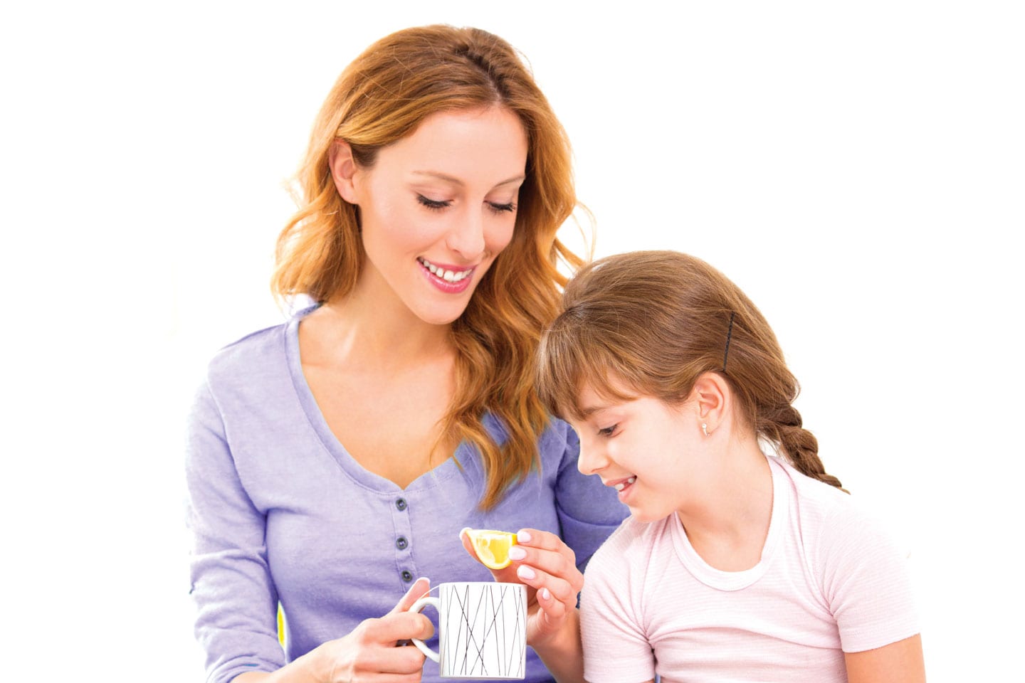 Mother squeezing lemon into cup for her young daughter