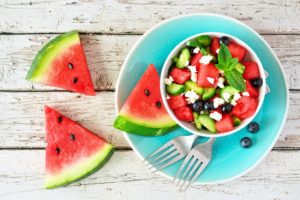 Watermelon salad with cucumber, blueberries and feta cheese. Top view table scene on a white wood background.