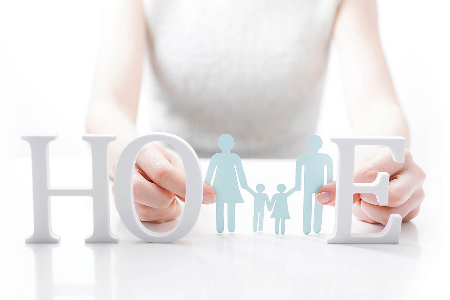 Woman holding cutout of a family between the word LOVE written out with block letters
