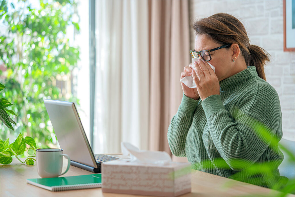 A woman sneezing into a tissue.