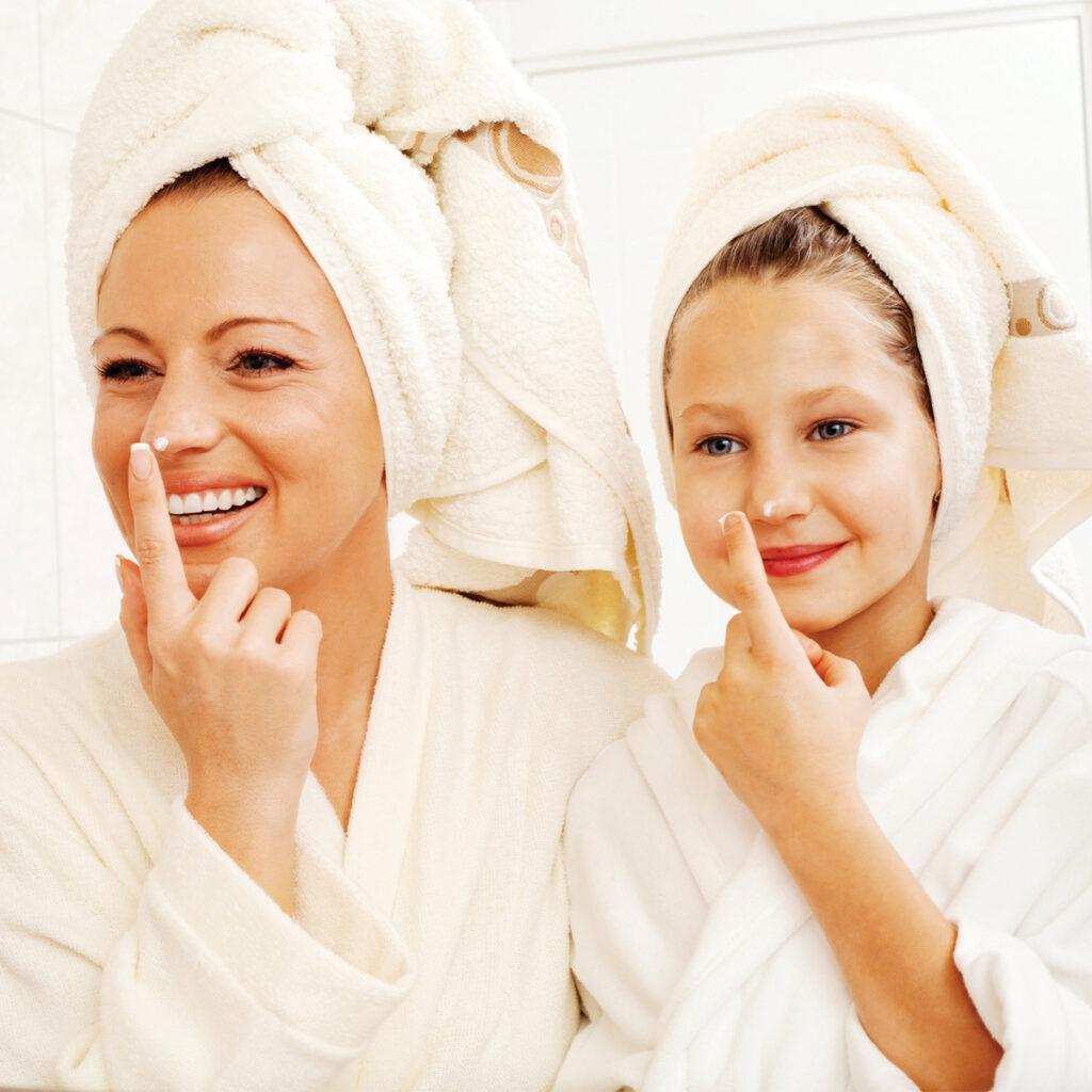 woman and daughter applying moisturizer together