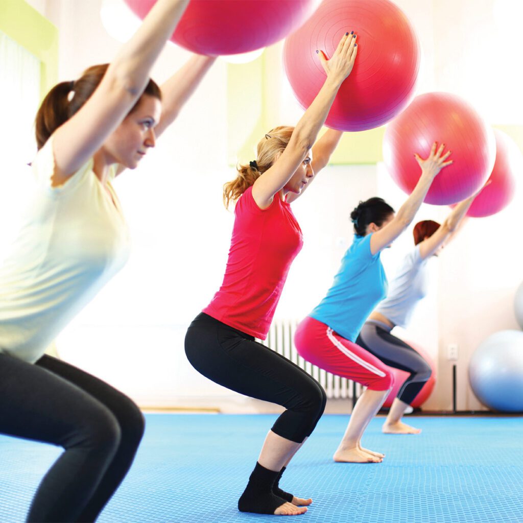 women in a fitness class holding up their exercise balls