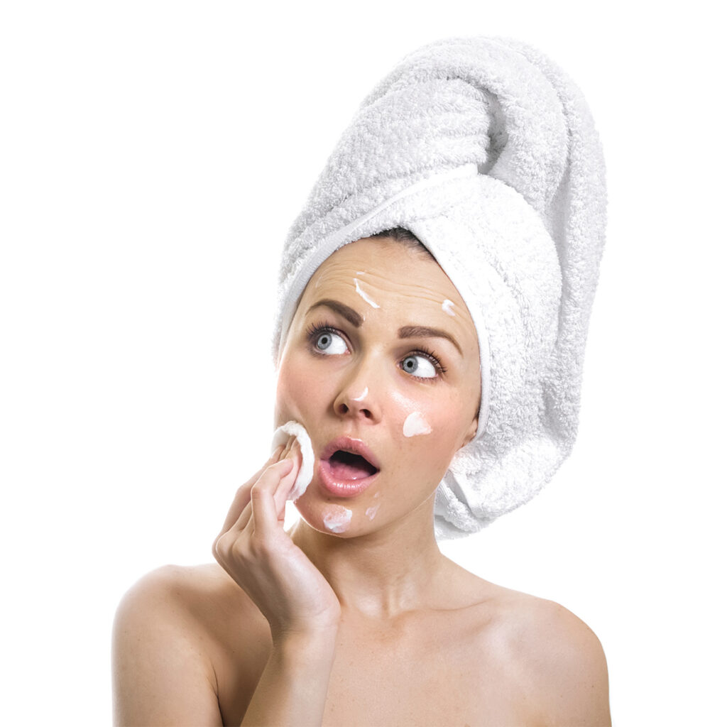 woman with bath towel wrapped on head and moisturizer on face