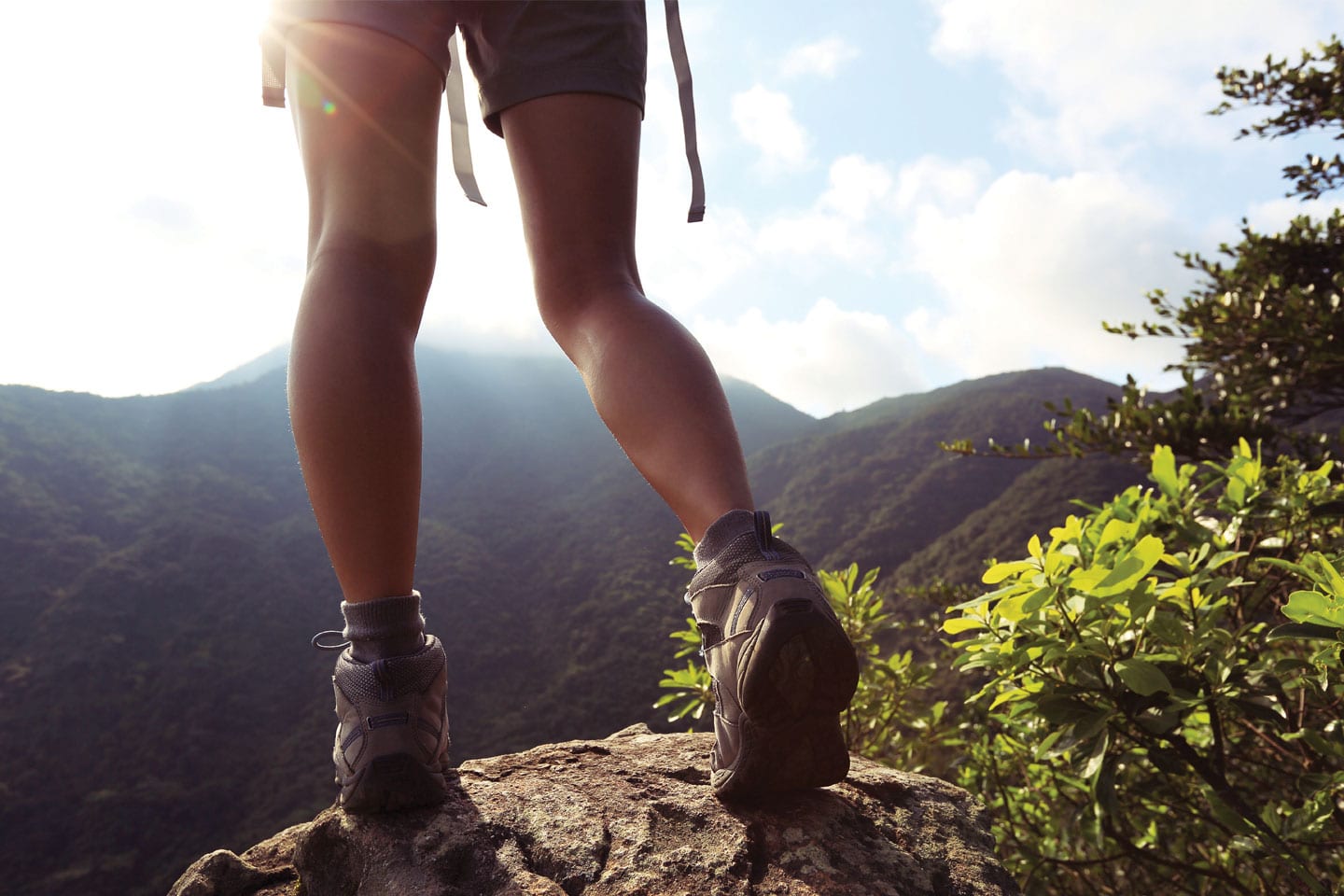Low shot of person's legs in hiking boots with the view in front of them being that of a series of rolling hills