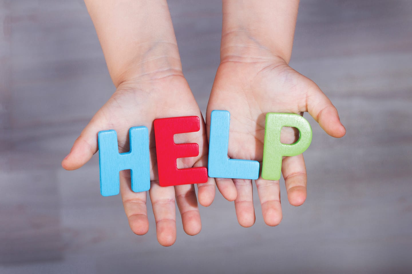 child's hands holding alphabet magnets spelling HELP