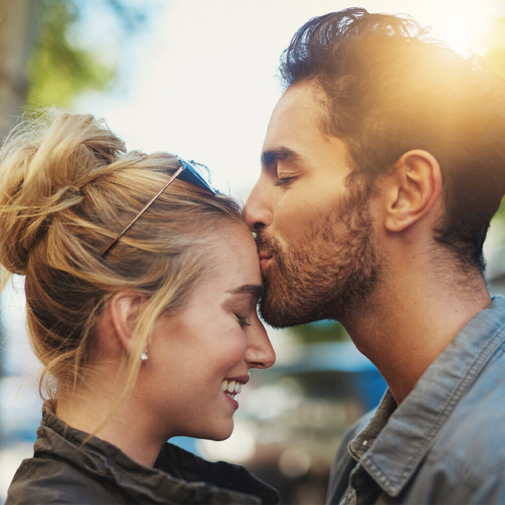 man kissing his girlfriend's forehead