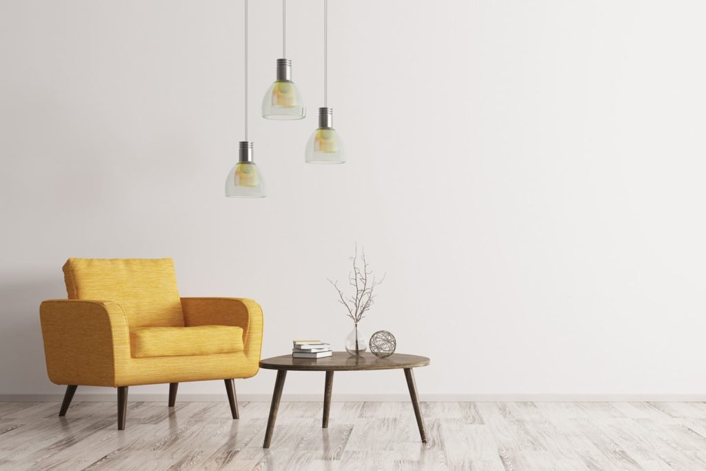 yellow couch, three hanging lights, and a small table with decorative items