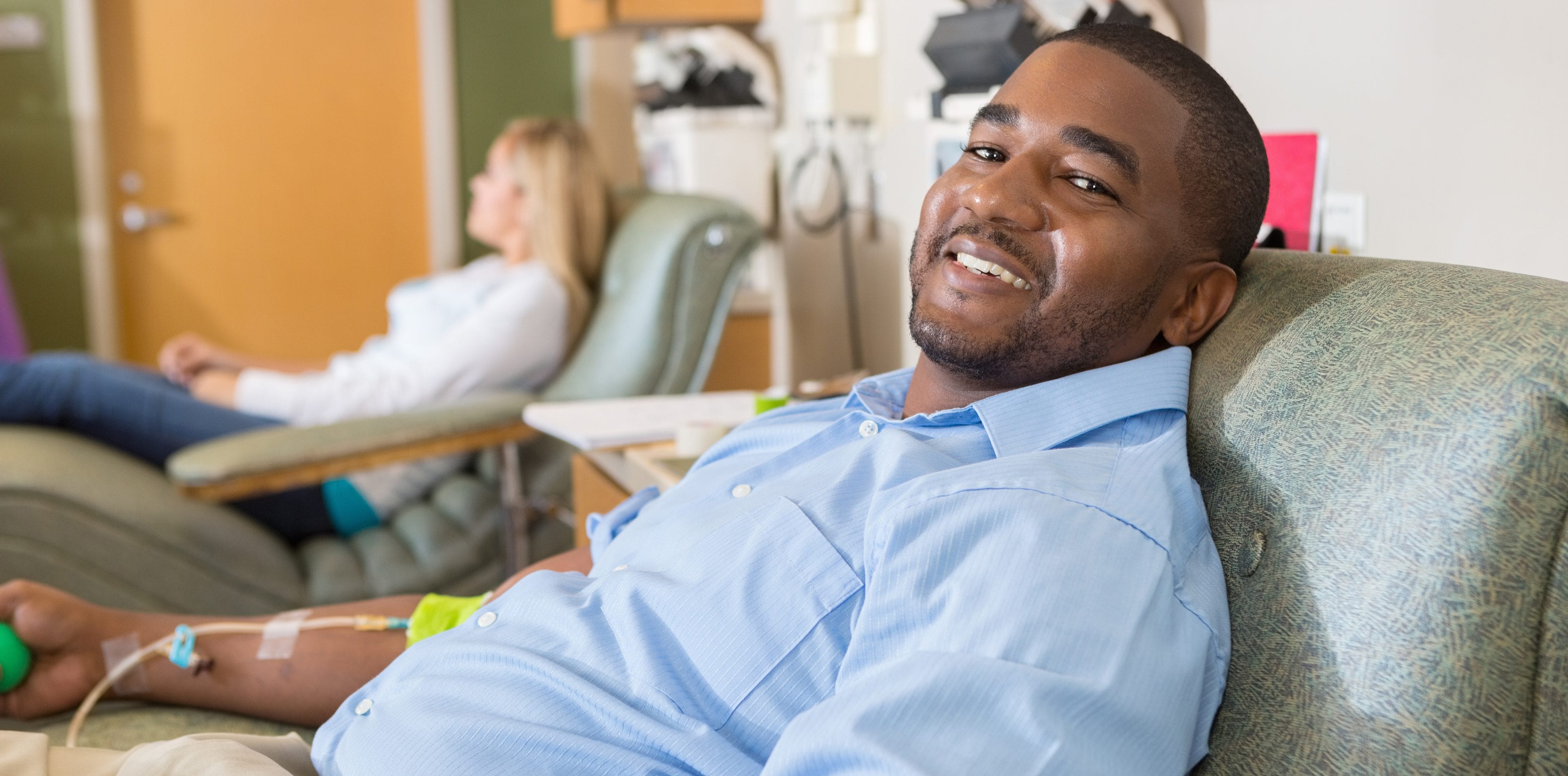 Happy African American man donating blood in hospital lab