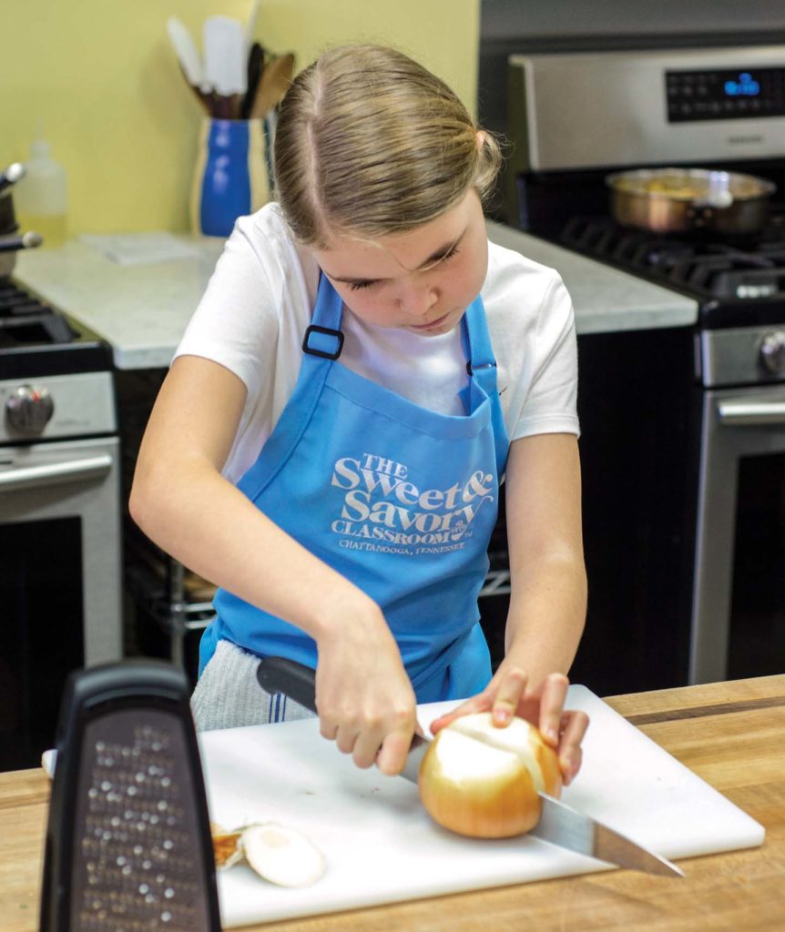 girl chopping an onion at cooking class in chattanooga