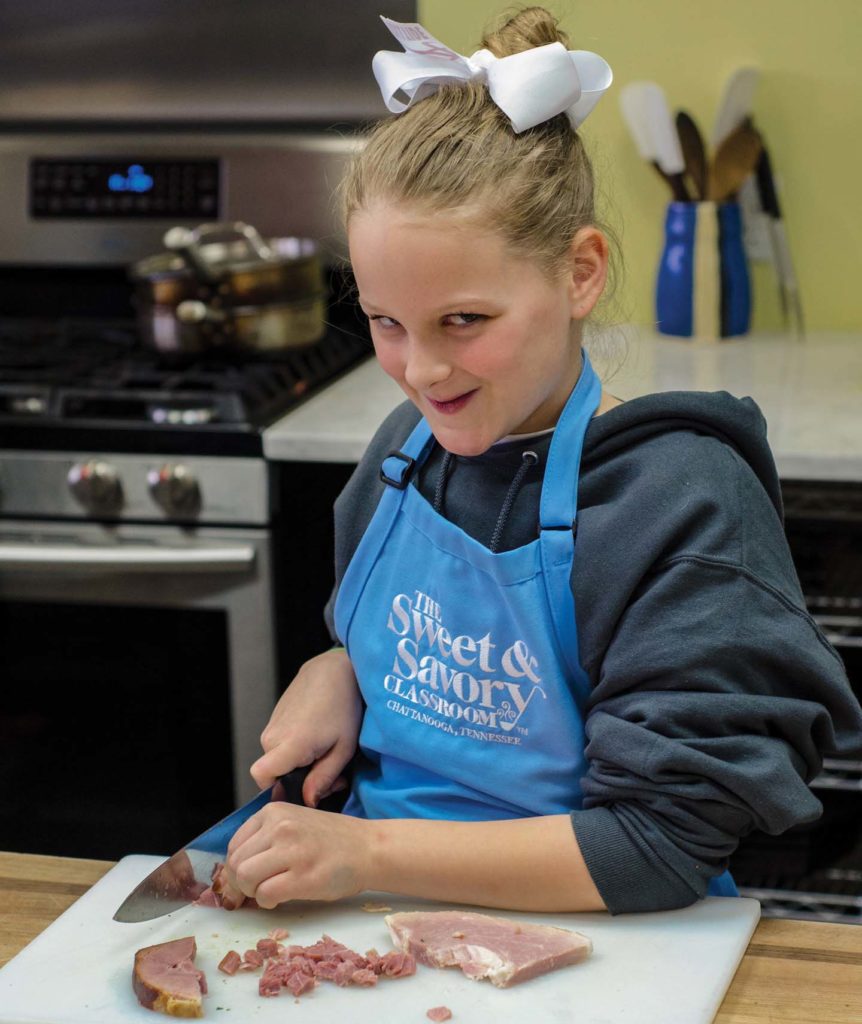 little girl chopping ham at cooking class in chattanooga