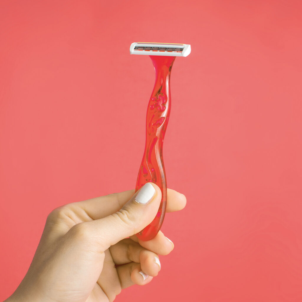 woman with white painted nail polish holding a shaving razor
