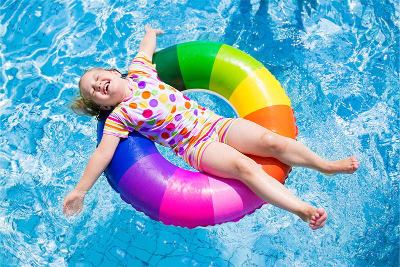 smiling child on rainbow inflatable in swimming pool