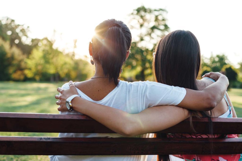 woman with arm around grown daughter on park bench chattanooga