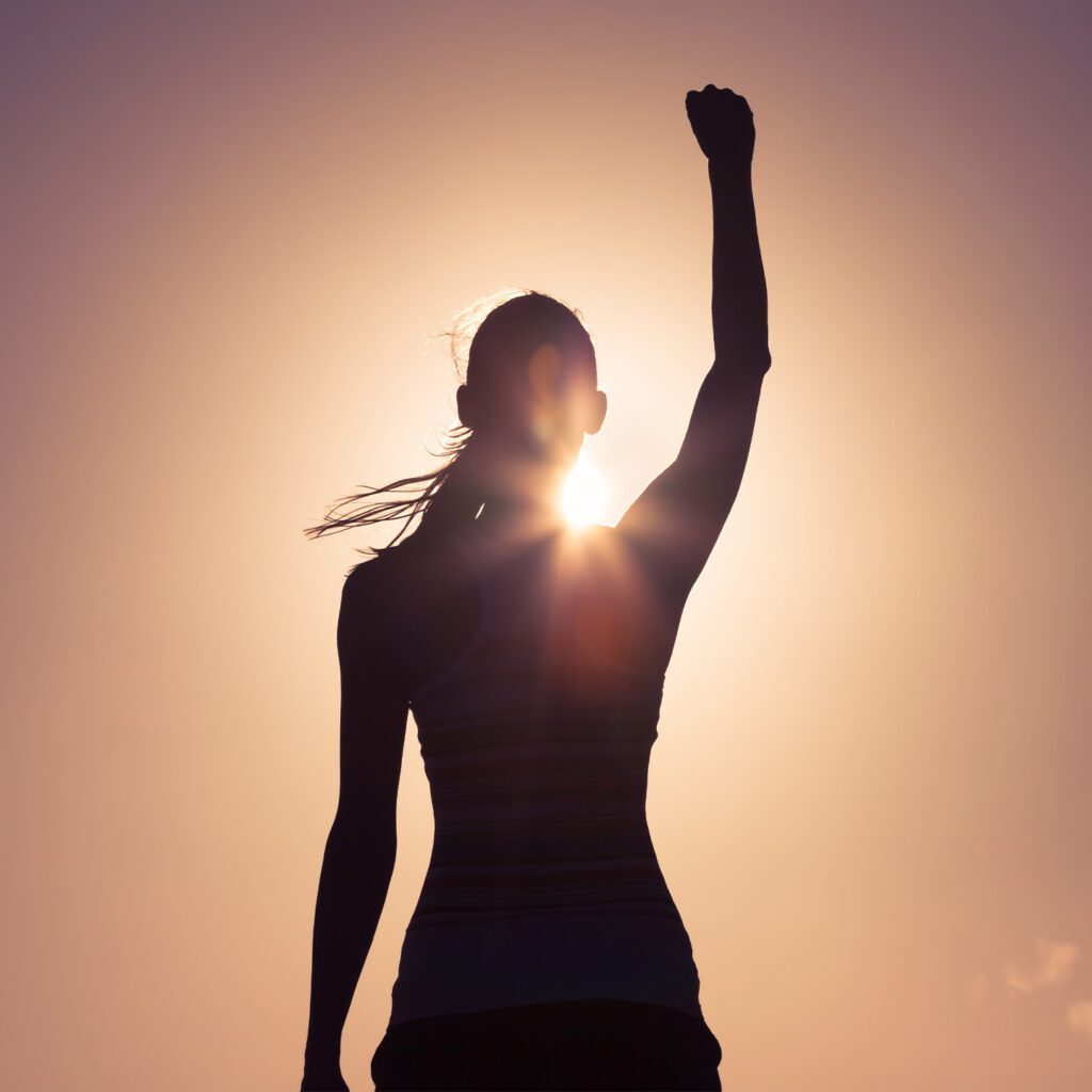 flawesome woman backlit with fist in air
