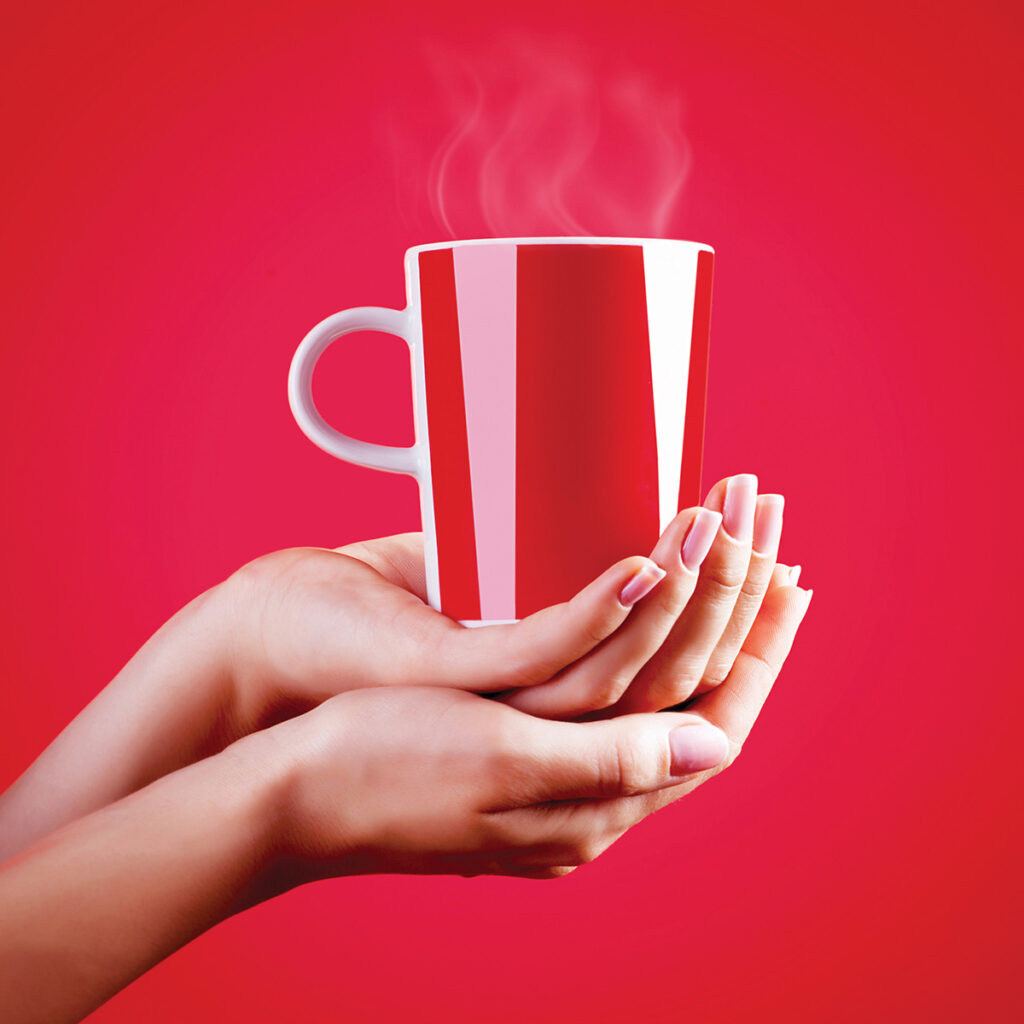two hands holding a hot red mug in red background