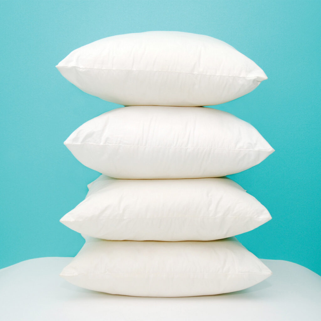 4 white pillows stacked on top of each other with blue background