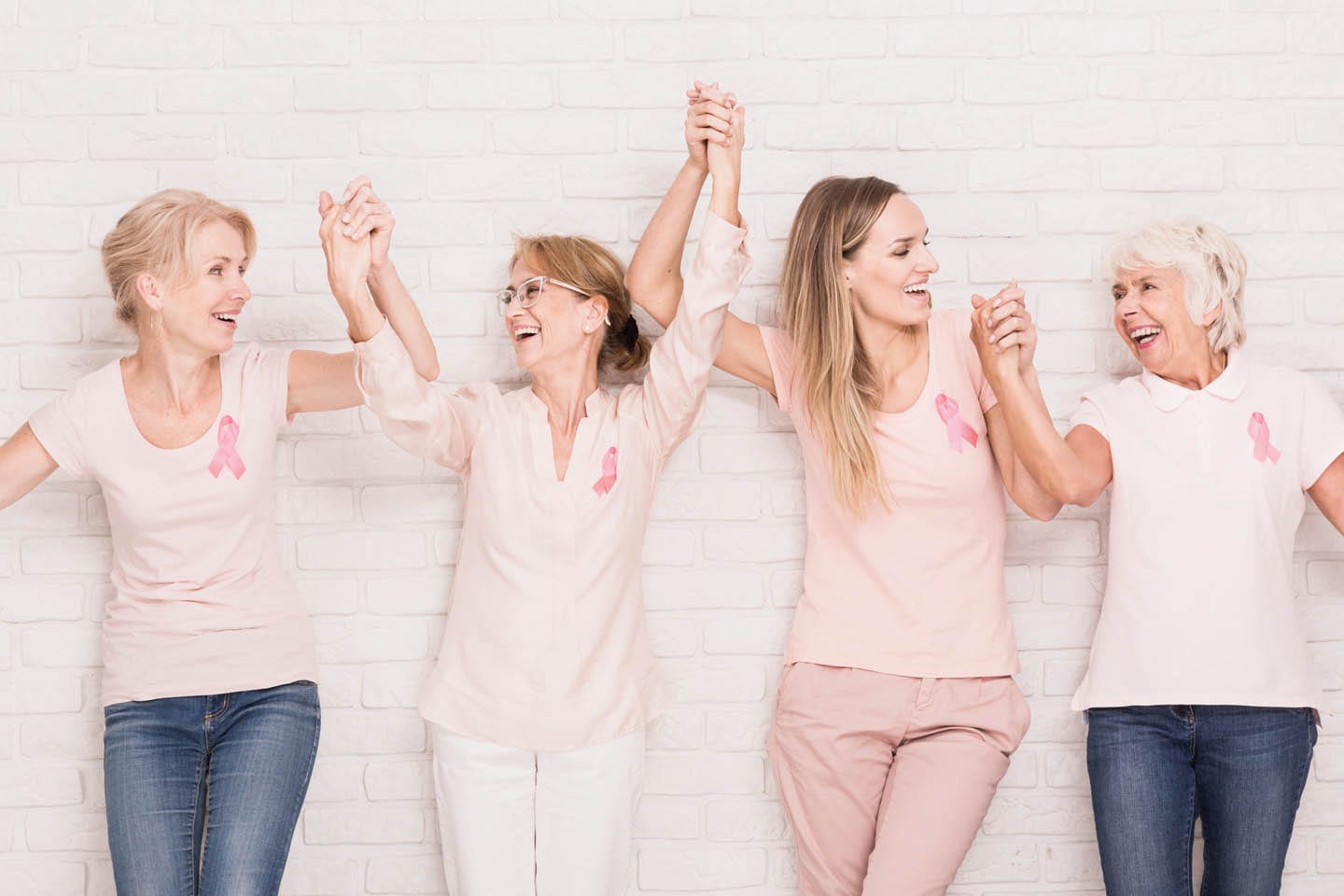 mature smiling women holding hands in pink shirts with breast cancer ribbons chattanooga