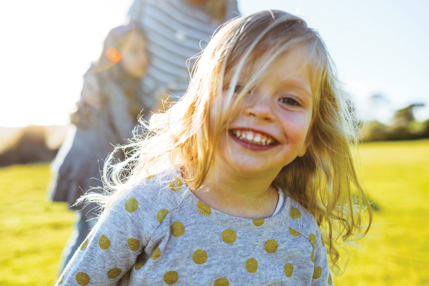 little girl smiling outside with family behind her in chattanooga