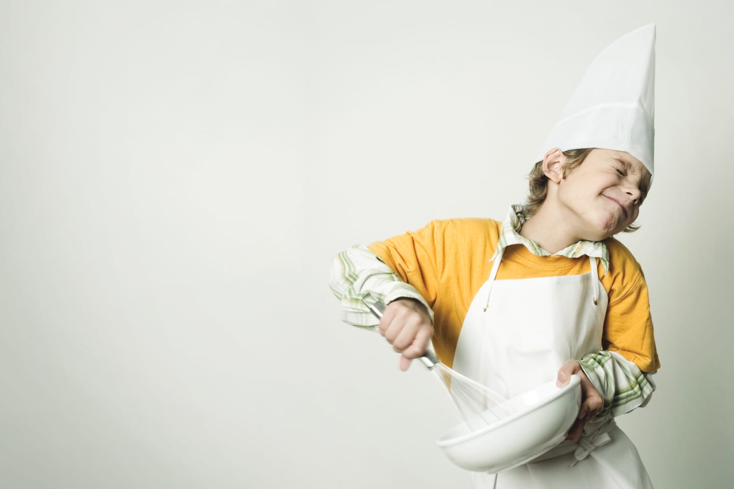little boy wearing a chef's hat and apron using a whisk in chattanooga