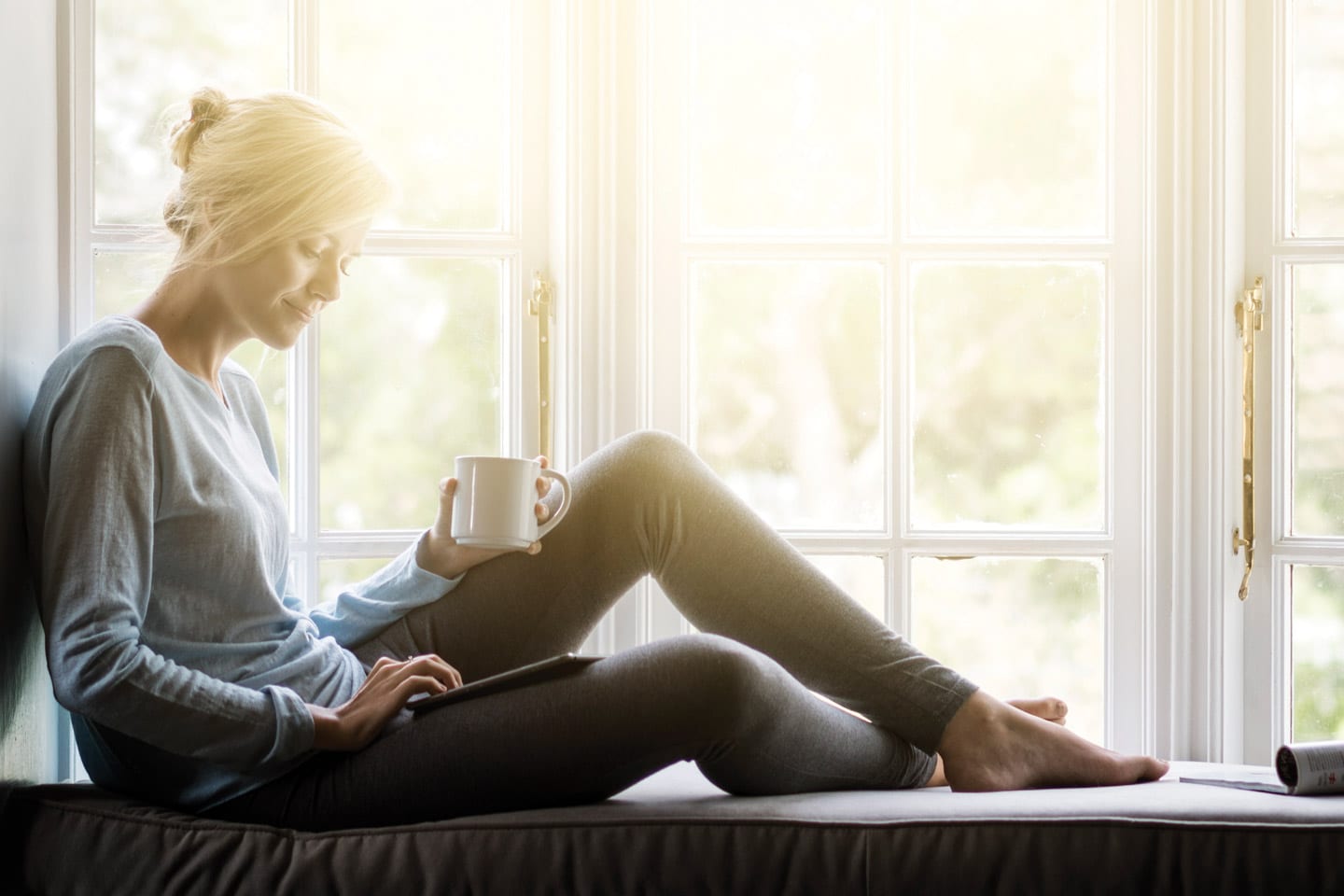 woman sitting in window seat with cup of coffee in the morning in chattanooga