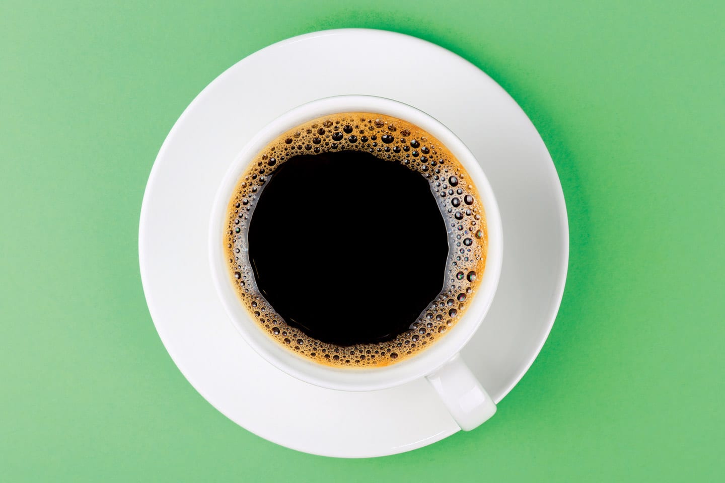 cup of black coffee in a white cup and saucer on green background in chattanooga