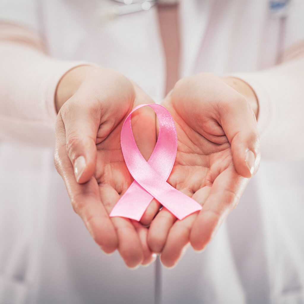 doctor's hands holding breast cancer pink ribbon