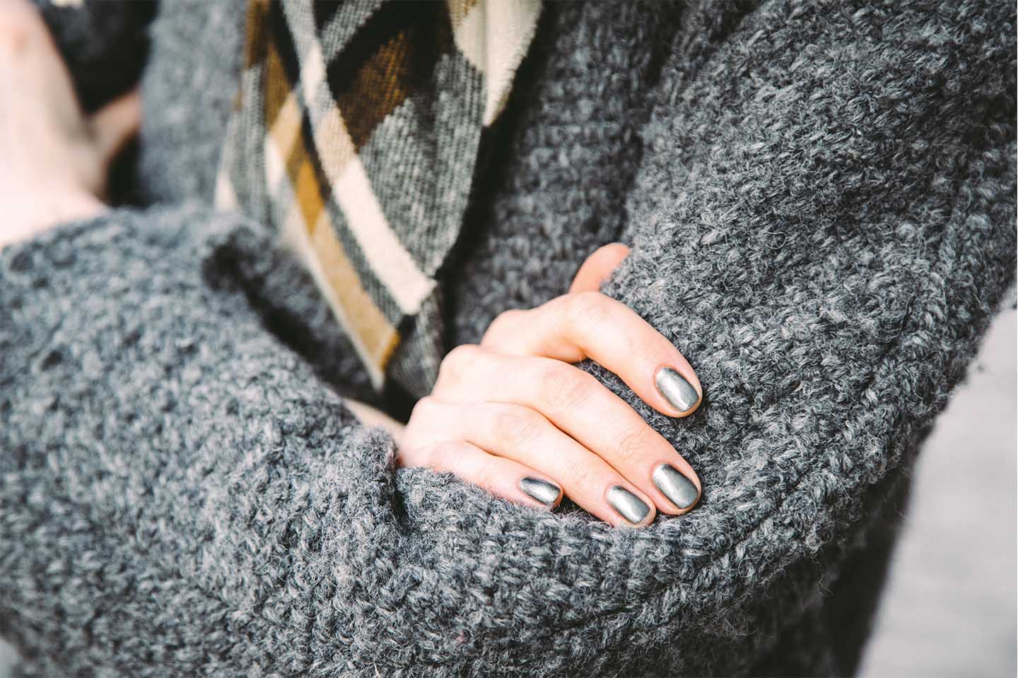 woman in gray sweater showing off silver nail polish manicure in chattanooga