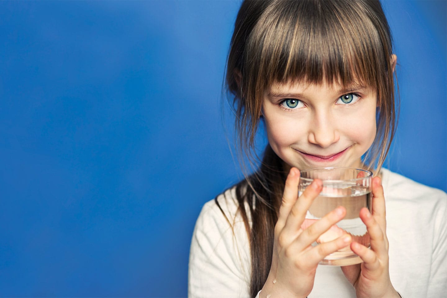 little girl drinking a glass of water on a blue background in chattanooga