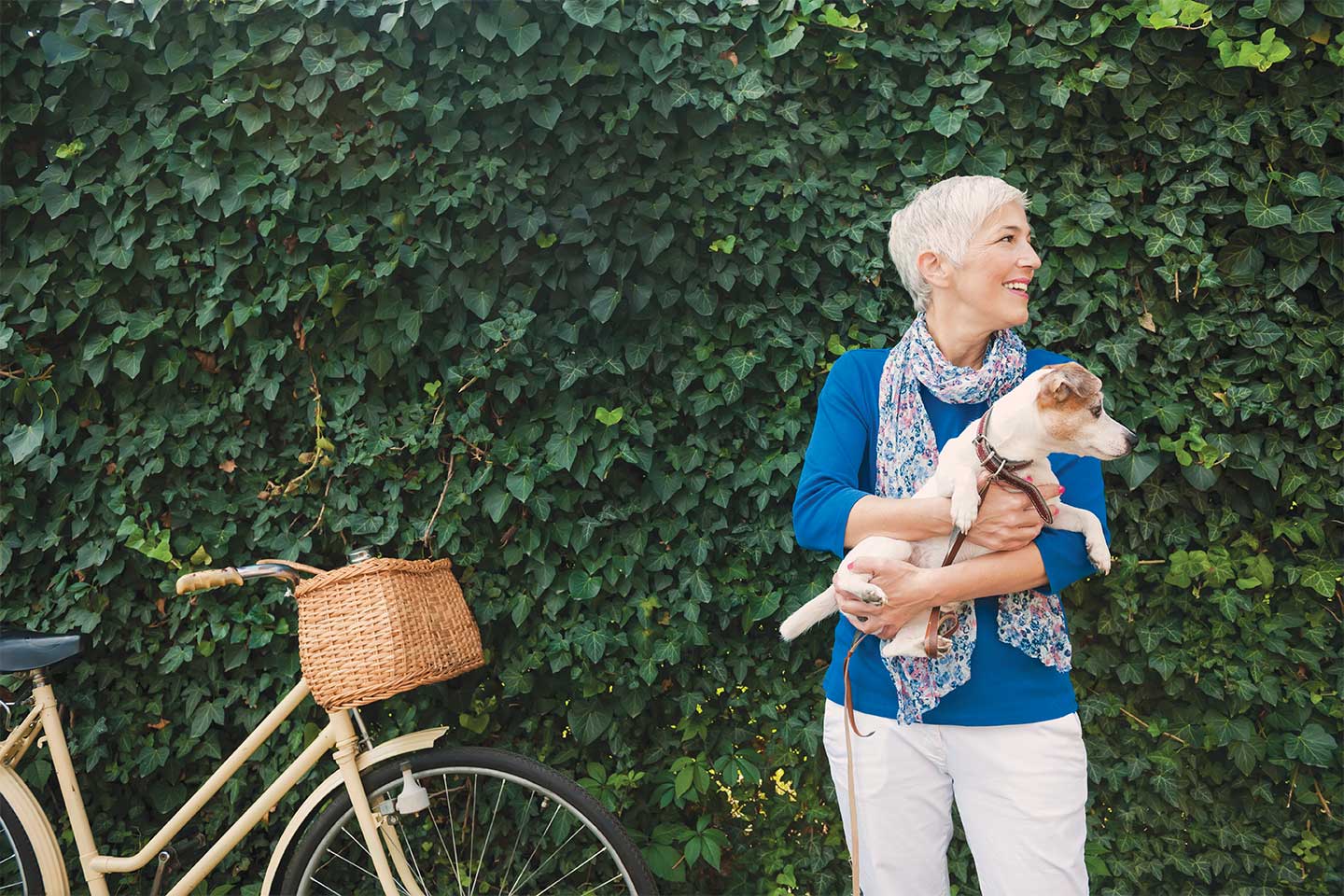 mature woman smiling and holding a dog standing next to her bicycle in chattanooga