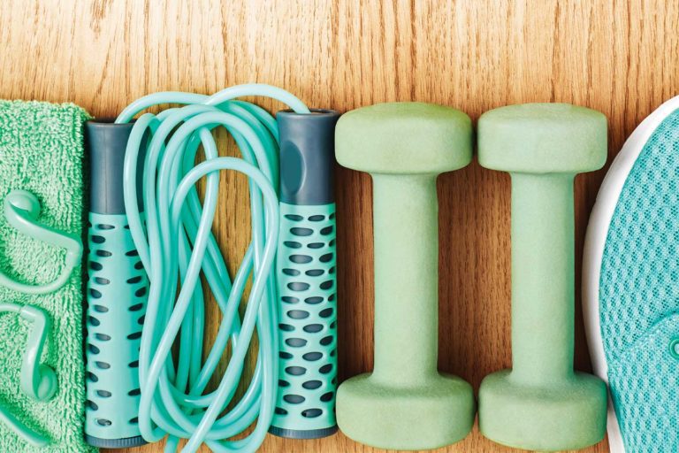 towel, earbuds, jump rope, hand weights, and tennis shoes fitness items flatlay