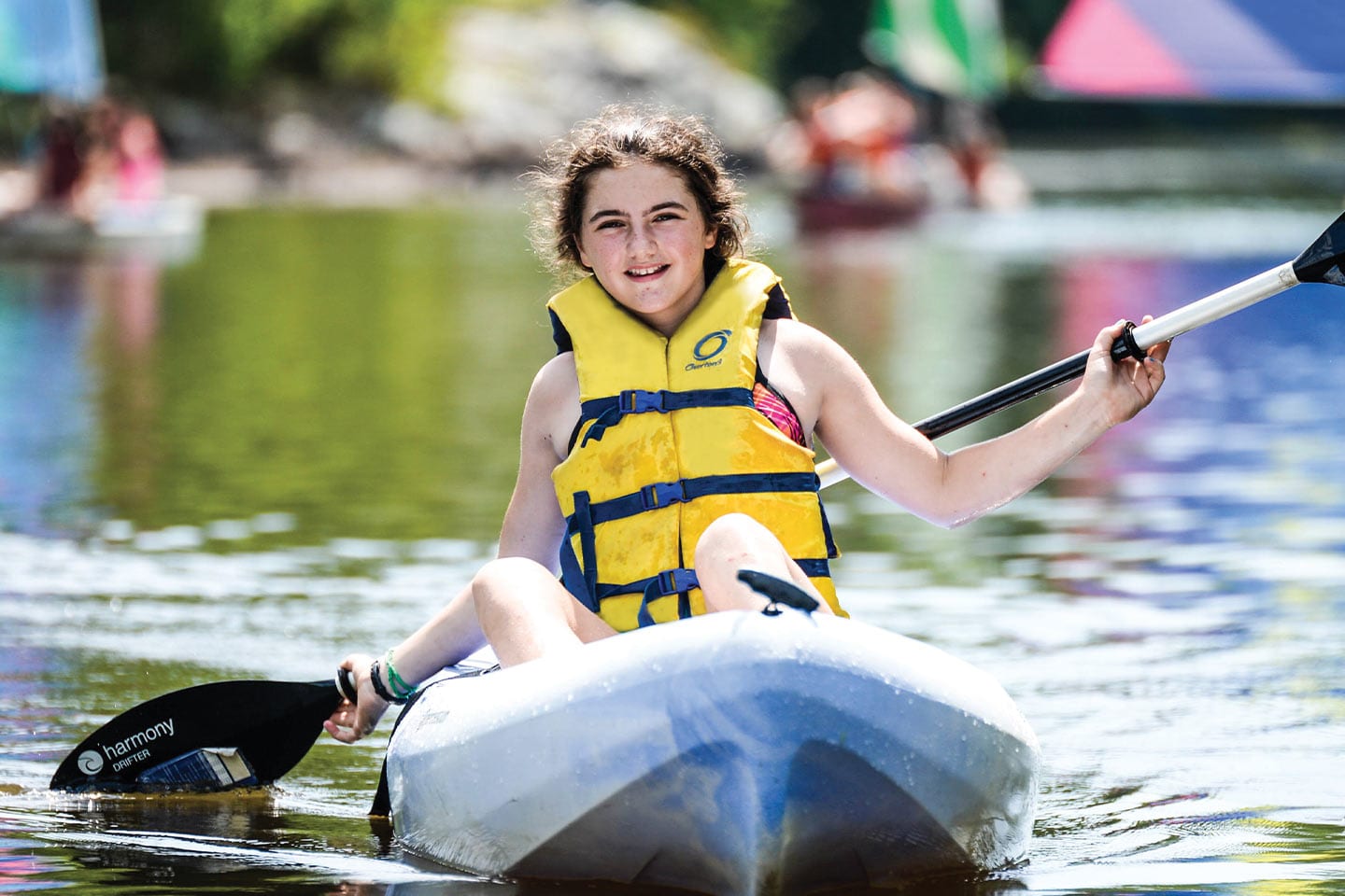 smiling girl paddling in a canoe at camp juliette low