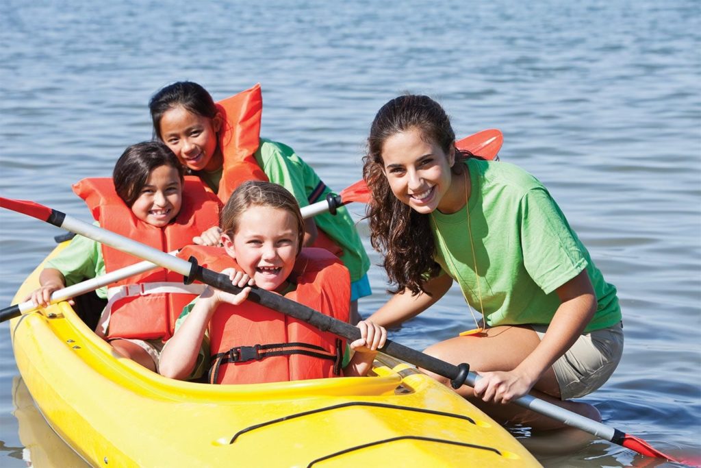 kids in kayak with camp counselor