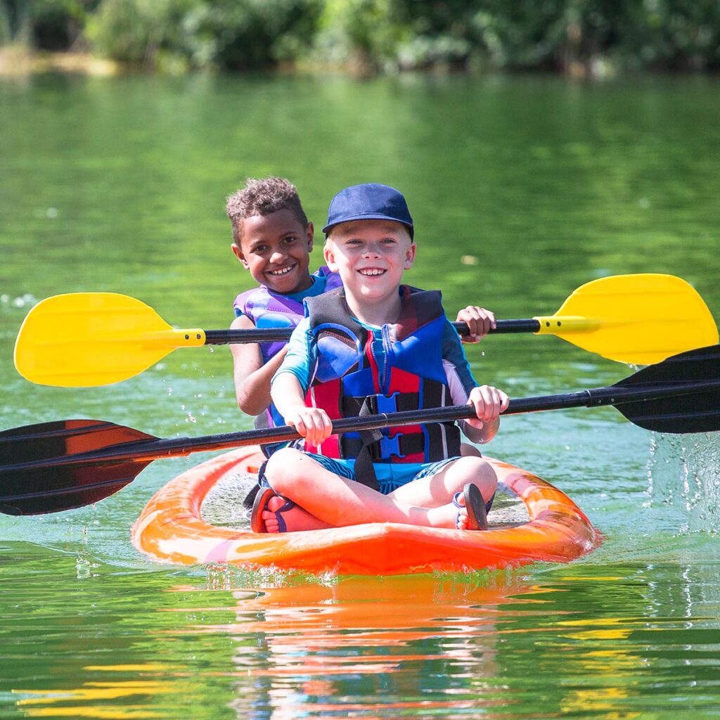 kids paddling on a lake during summer camp