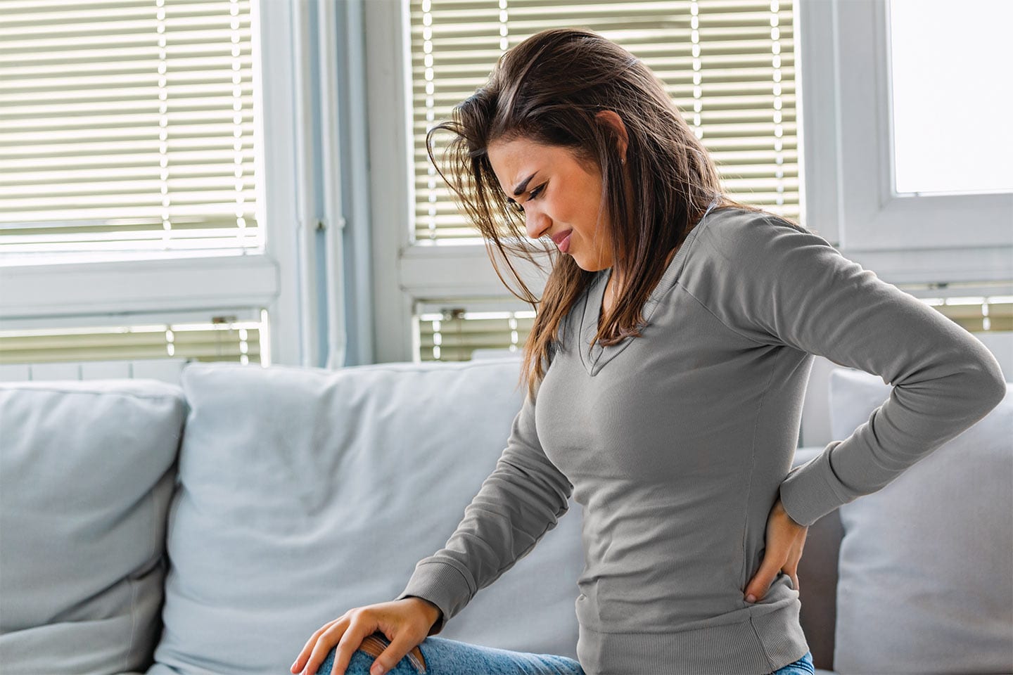 woman sitting on couch with spine pain