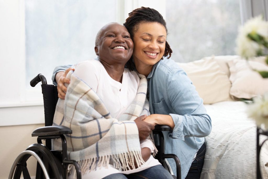 woman hugging her mother in a wheelchair as they move her into assisted living
