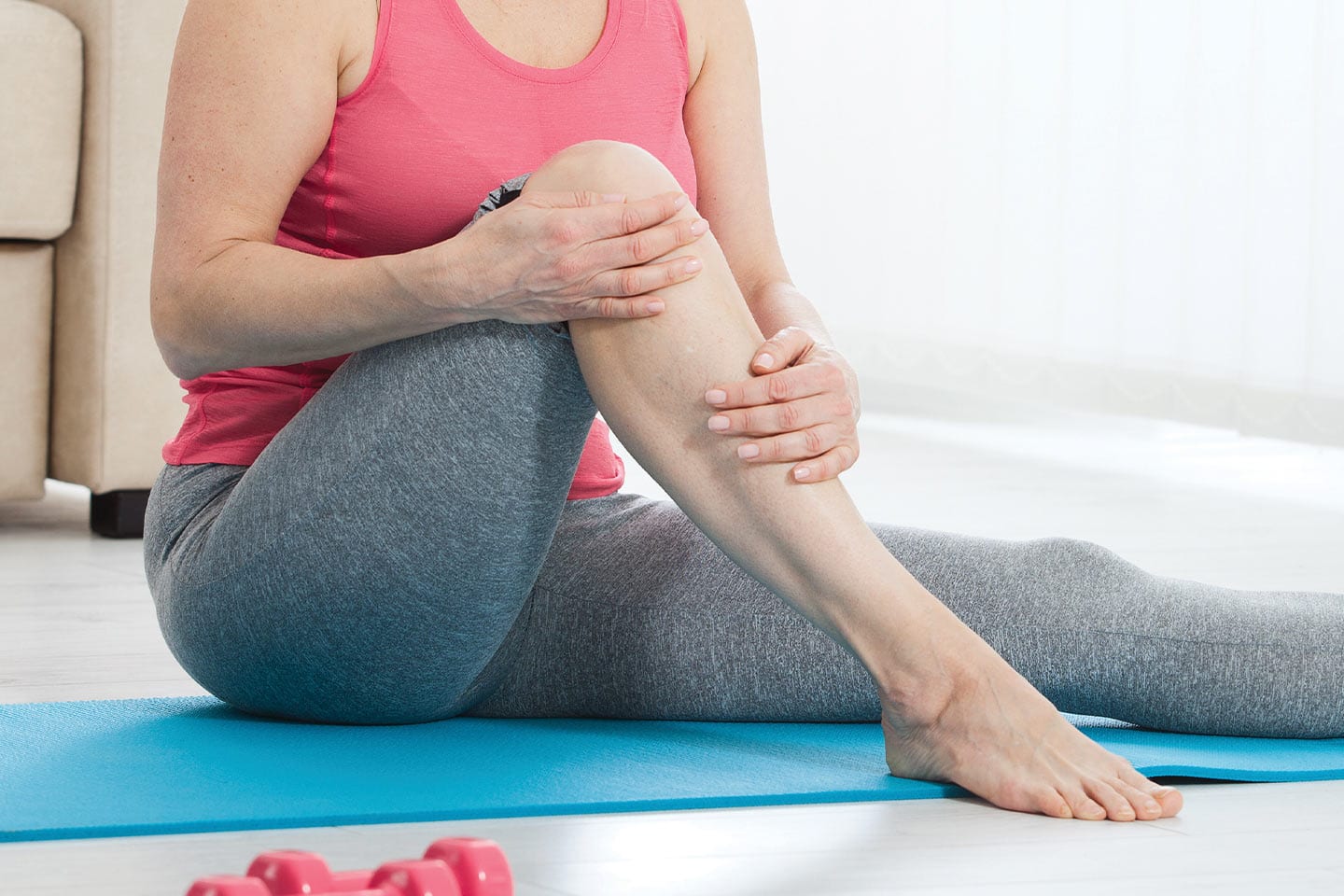 older woman doing yoga with her hands on her leg free of varicose veins