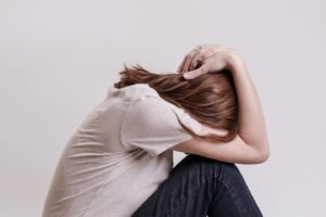 woman hunched over with hands on head suffering from anxiety