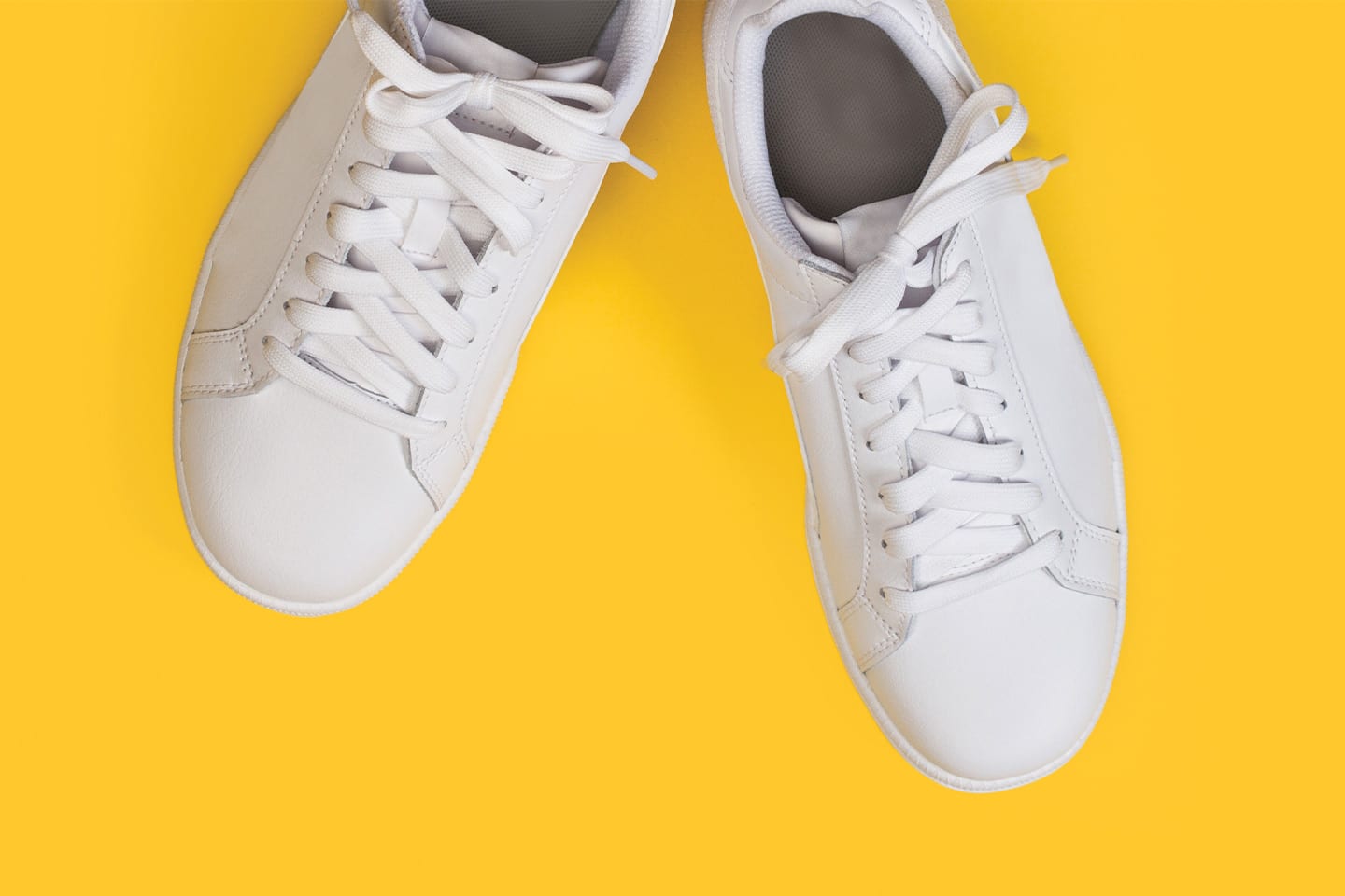 white tennis shoes on yellow background