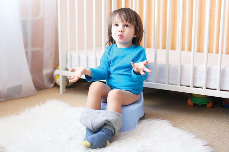 little boy shrugging while sitting on toddler potty