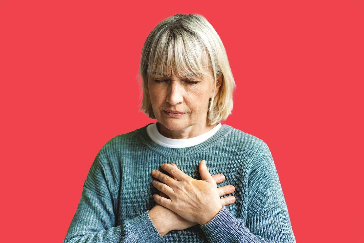 older woman with hands to chest because of heart pain