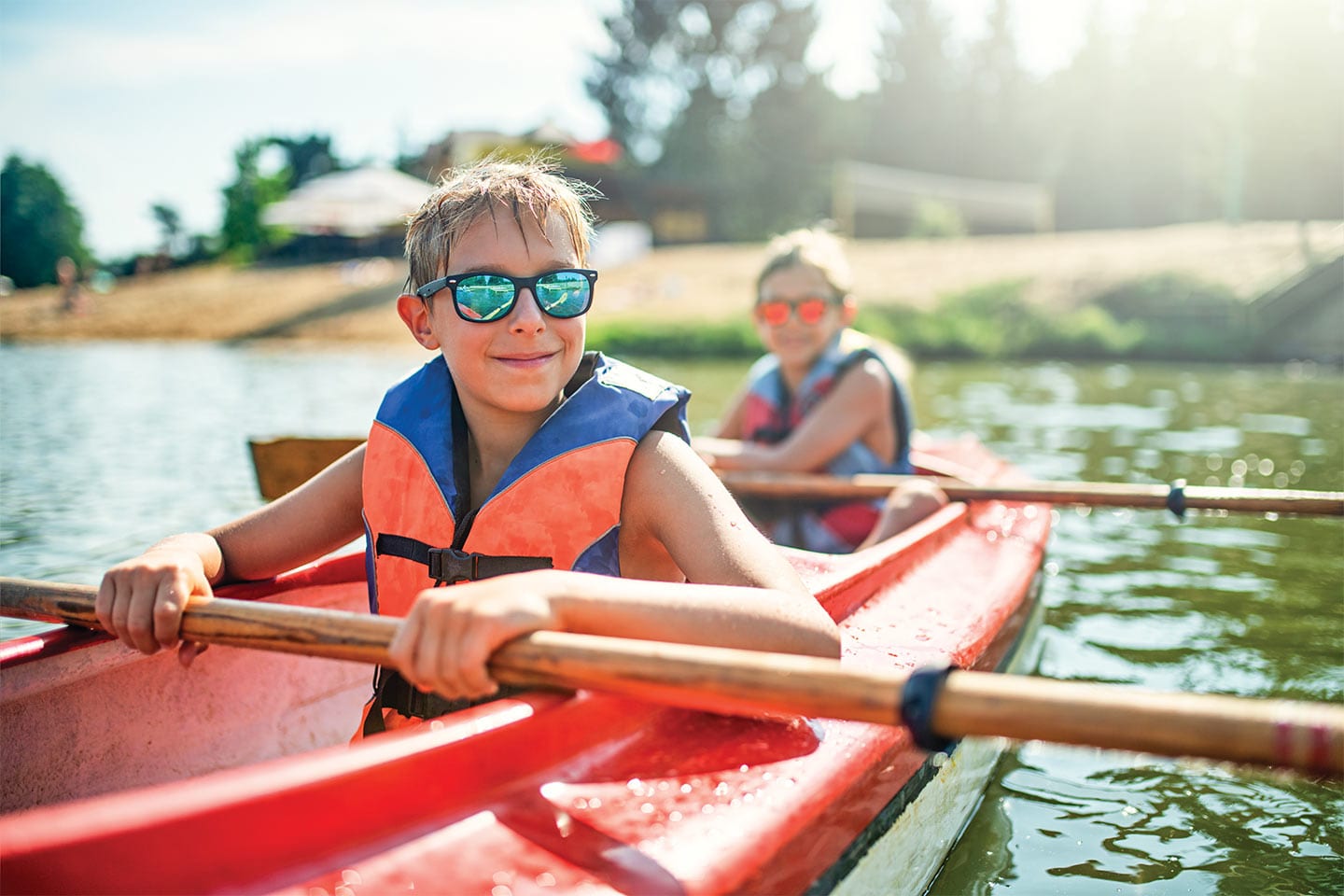 kids wearing life vests paddling a kayak