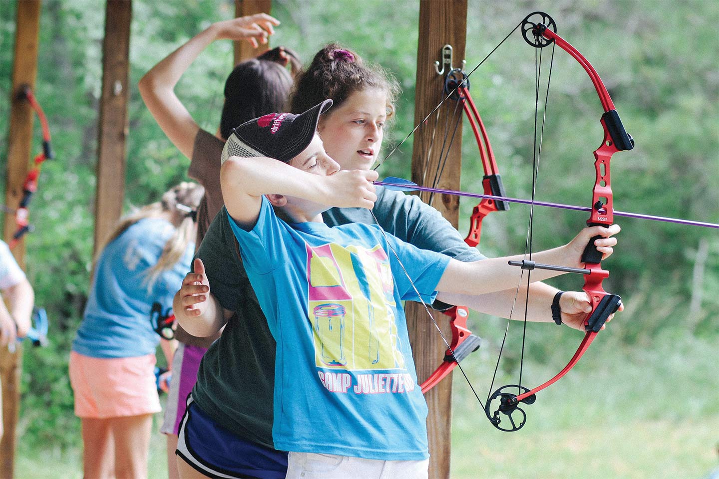 Little girl shooting a bow and arrow at Camp Juliette Low
