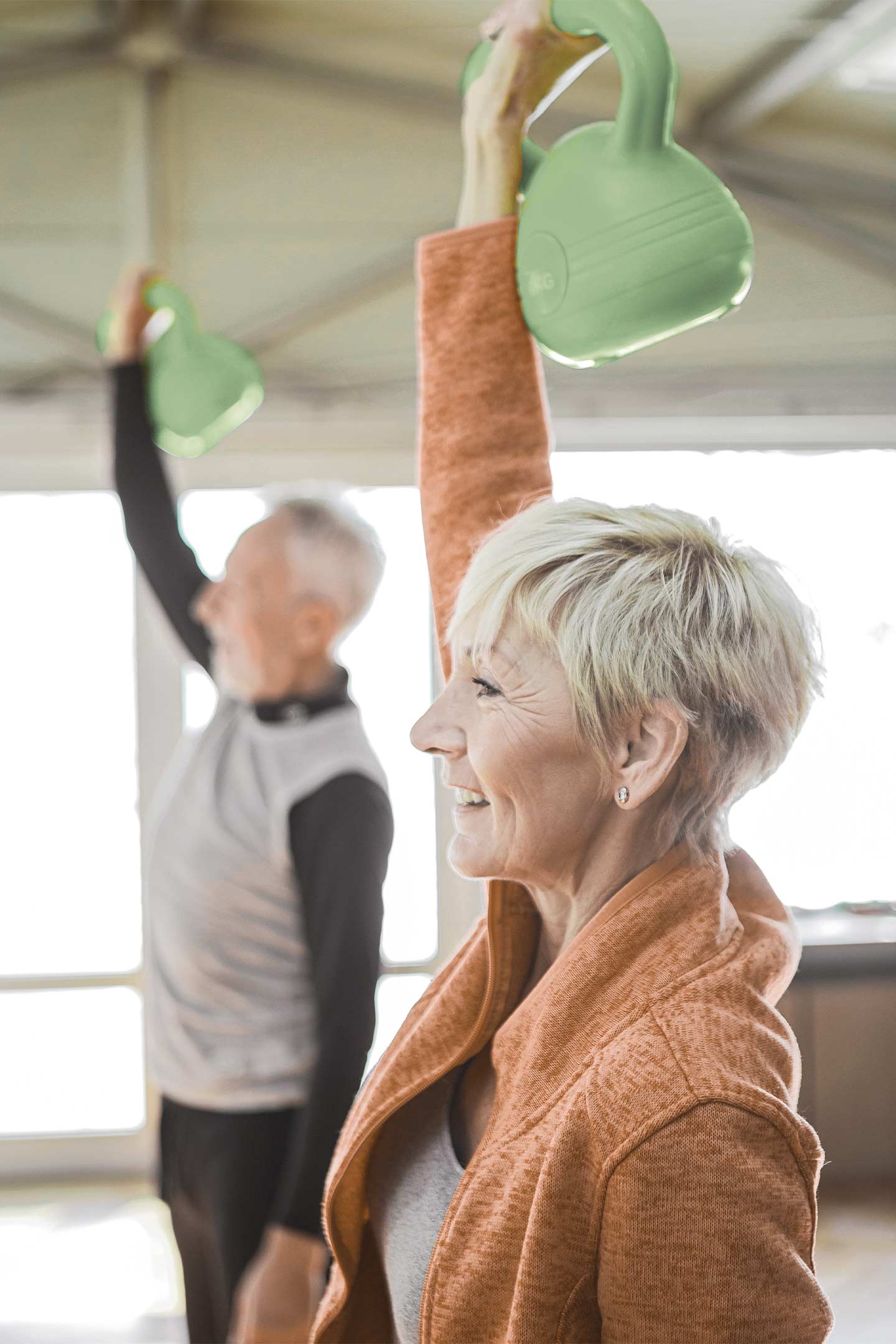 elderly man and woman lifting kettlebells